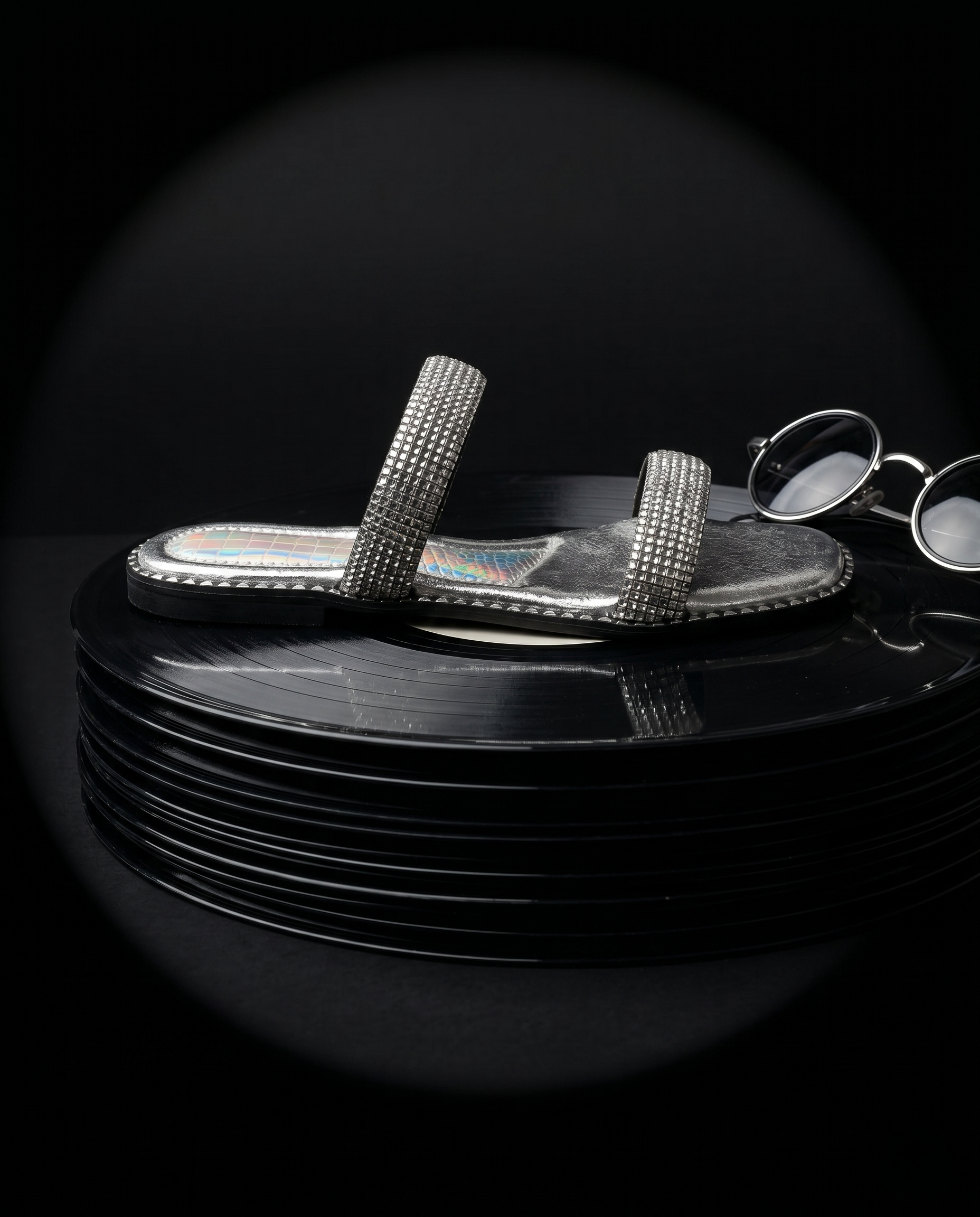 Crystalline Silver Flats on stacked vinyl records by Solemates by Palak — silver crystal double strap flat sandal with holographic lining and silver stud trim, dark studio backdrop