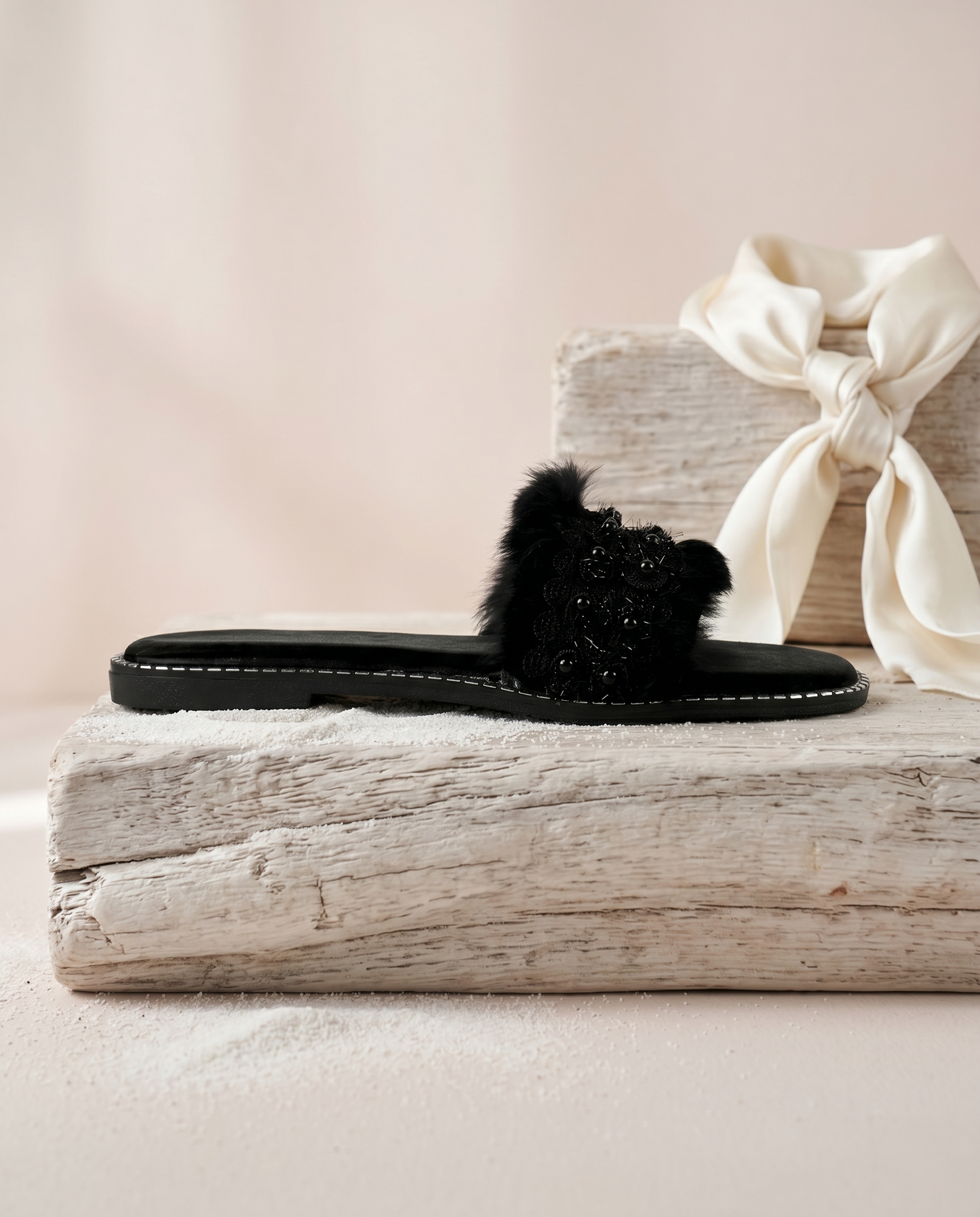 Furry Black flat slider side view on driftwood by Solemates by Palak — black fluffy fur strap with floral lace appliqué, silver stud sole trim and black suede-finish base