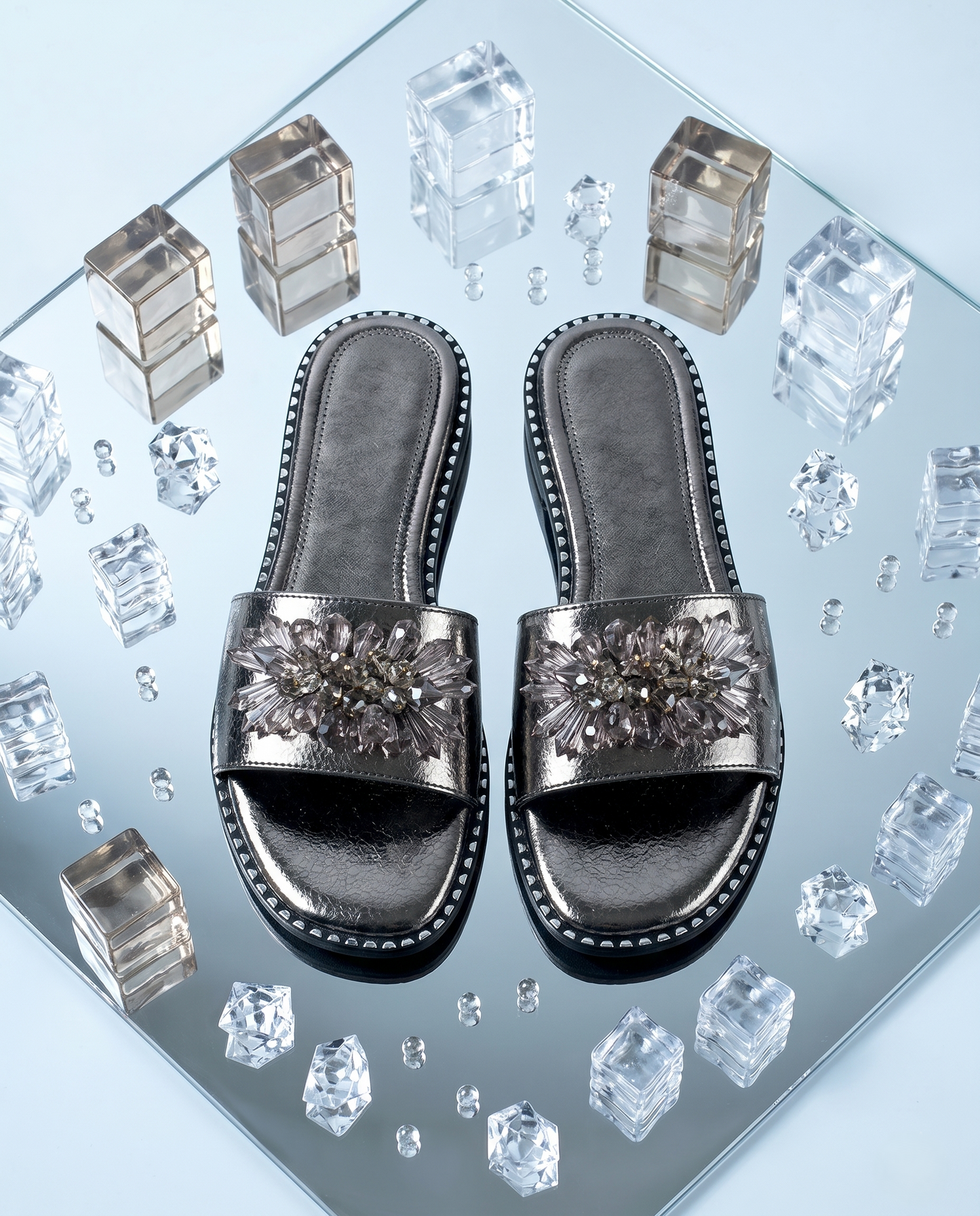Grey Mirage Flat Sliders top view on mirror surface with crystal cubes — gunmetal metallic sliders with smoky crystal floral brooch and studded sole trim by Solemates by Palak