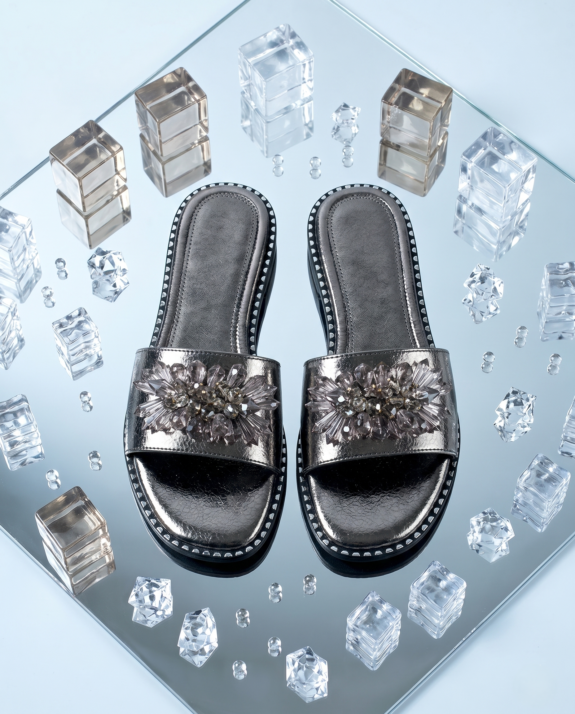 Grey Mirage Flat Sliders top view on mirror surface with crystal cubes — gunmetal metallic sliders with smoky crystal floral brooch and studded sole trim by Solemates by Palak