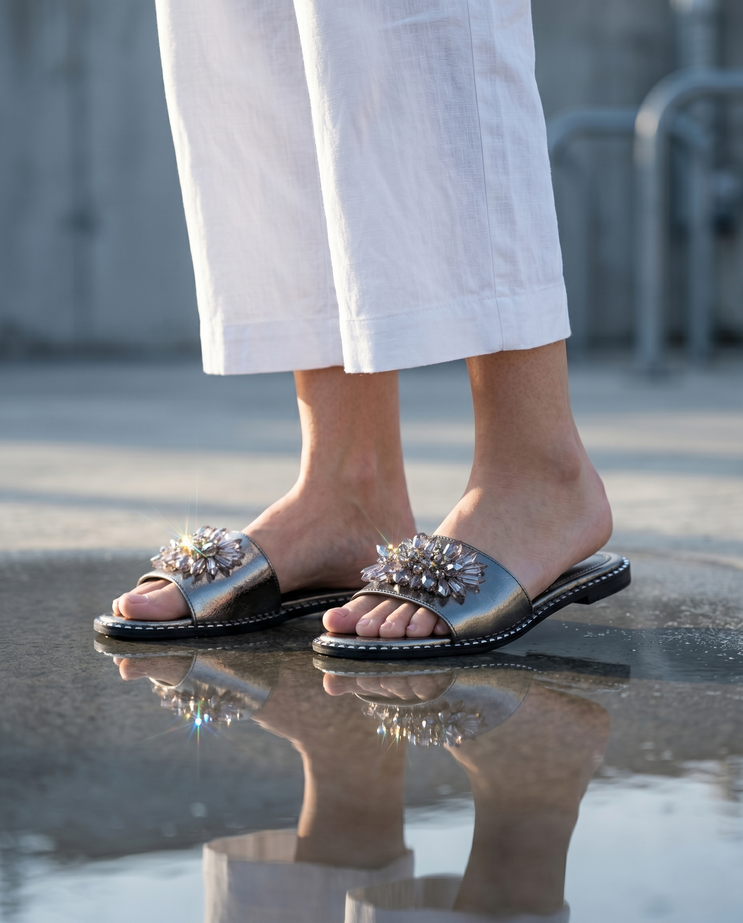 Grey Mirage Flat Sliders worn with white linen trousers — gunmetal metallic flat sliders with crystal floral brooch embellishment by Solemates by Palak